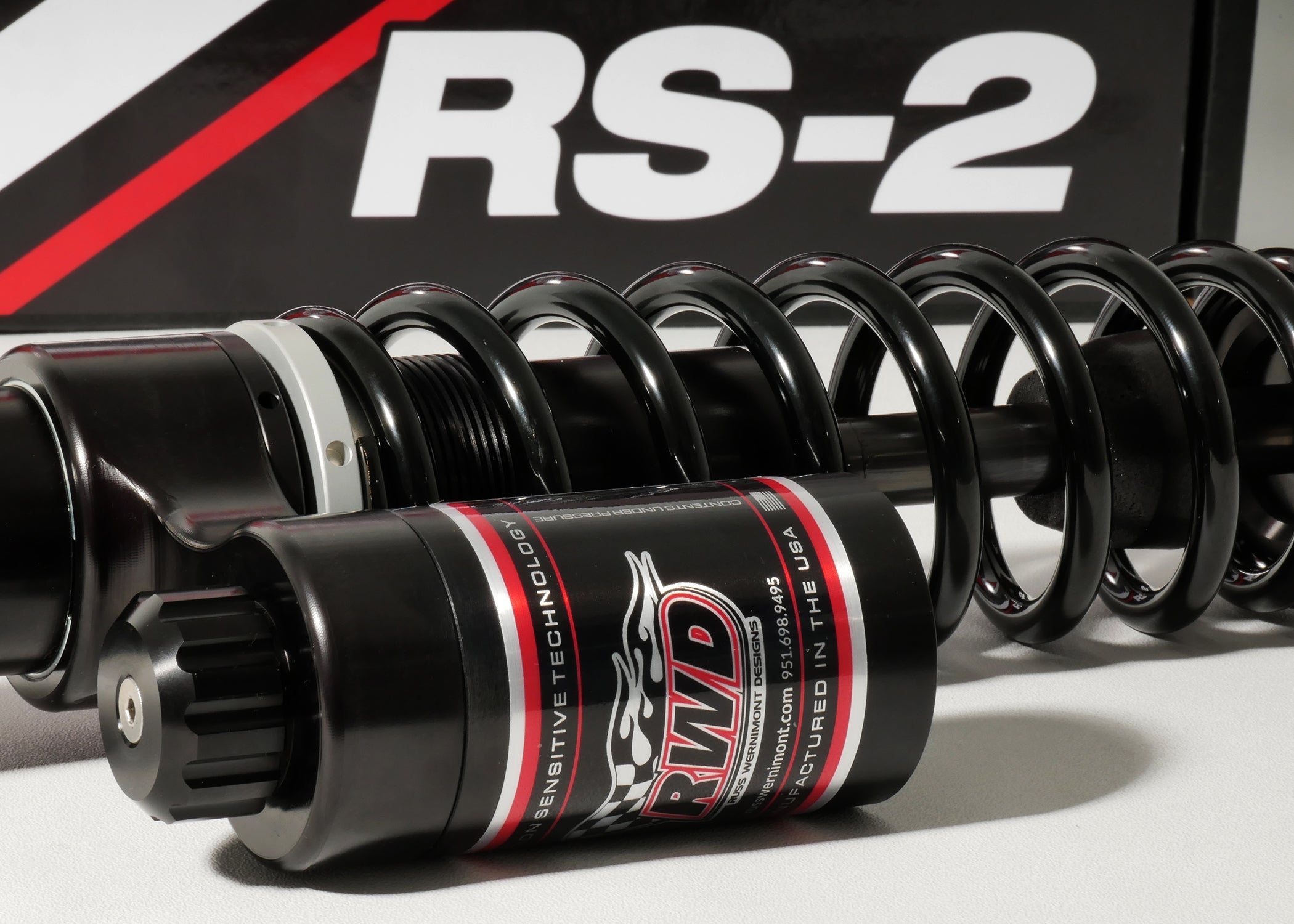 A close-up of the RWD V-Twin RS-2 Dyna shock absorber, featuring a black spring and body with silver accents, and the RWD logo prominently displayed on the reservoir.