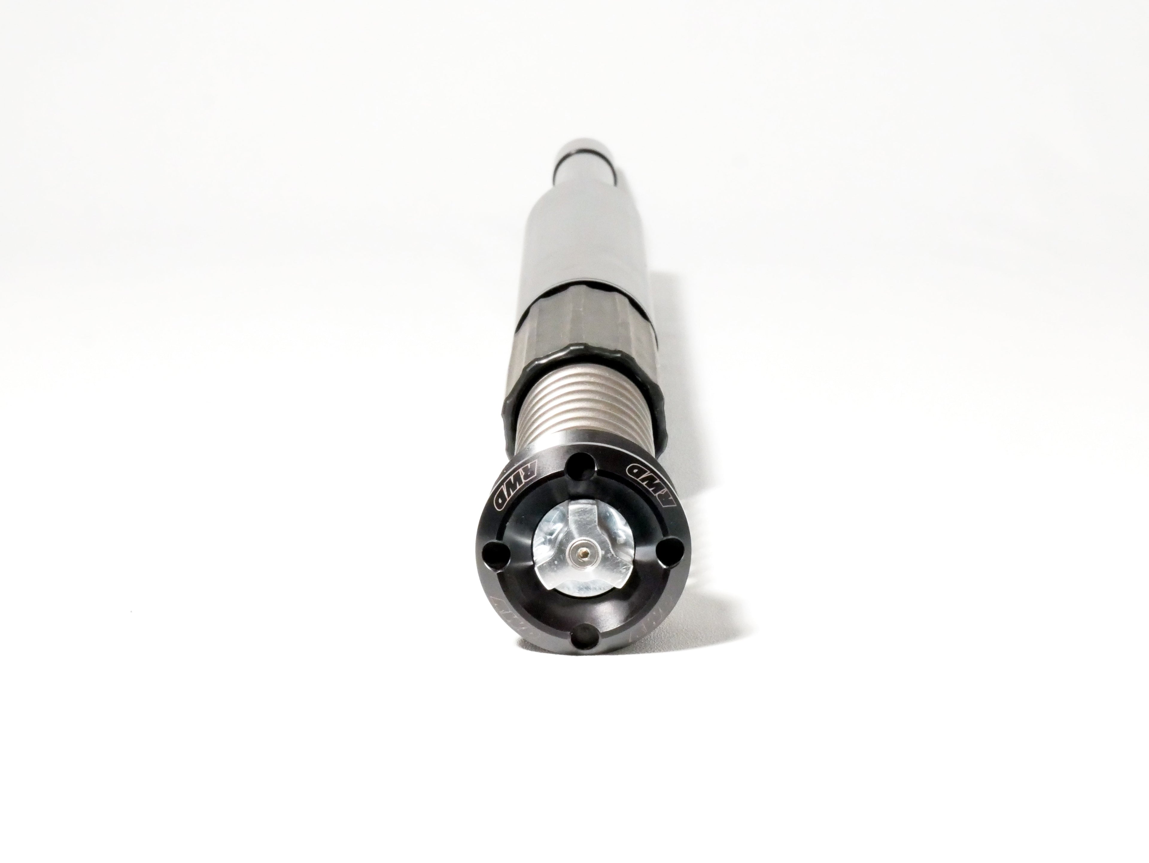A close-up, eye-level shot of an RWD V-Twin RS-1F front fork cartridge, showcasing its black anodized cap with the RWD logo, silver spring, and gray body against a clean white background.